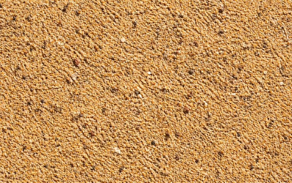 Close-up da textura de areia média, grãos visíveis e tom dourado